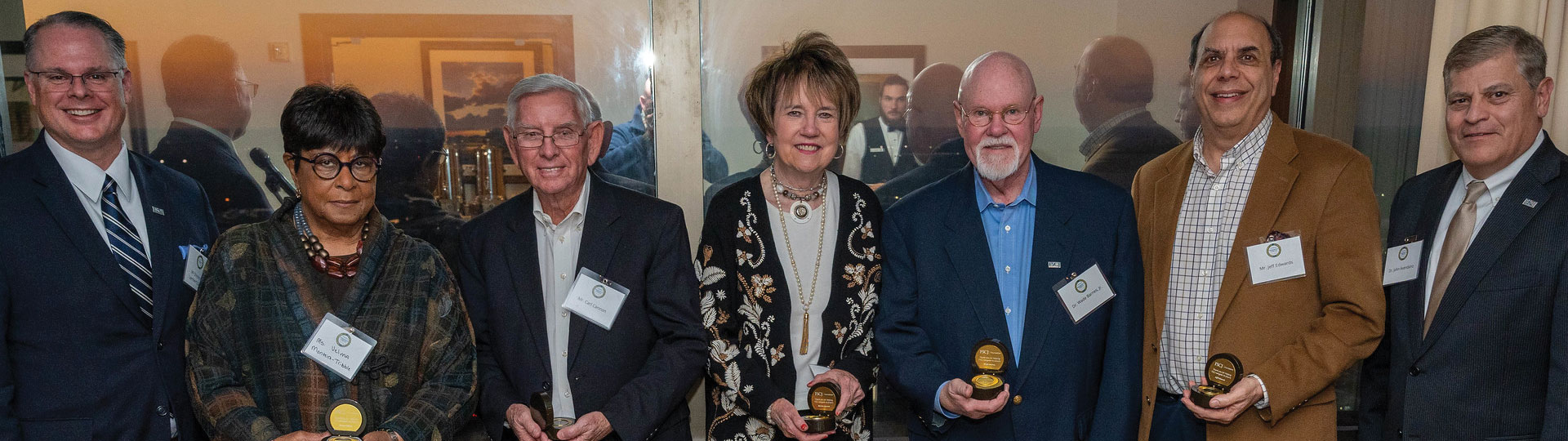 Men and women looking at camera holding award